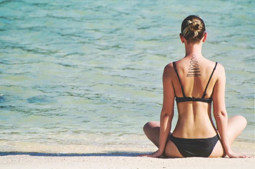 women in yoga pose for breast enlargement facing sea