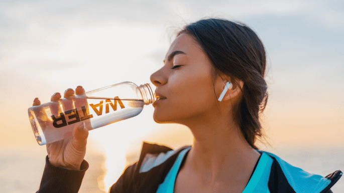 girl drinking water from glass bottle