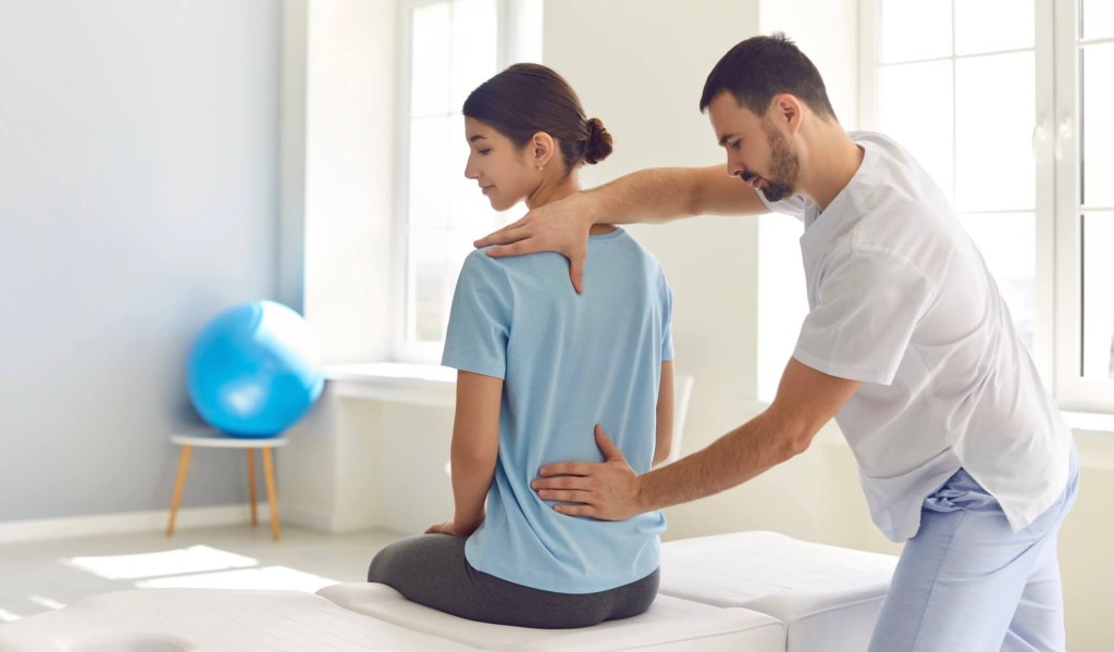 a physiotherapist helping woman with low back pain 
